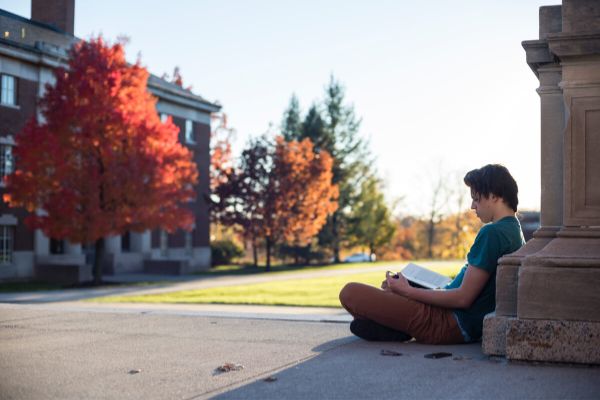Student sitting on campus of Unversity of Rochester.