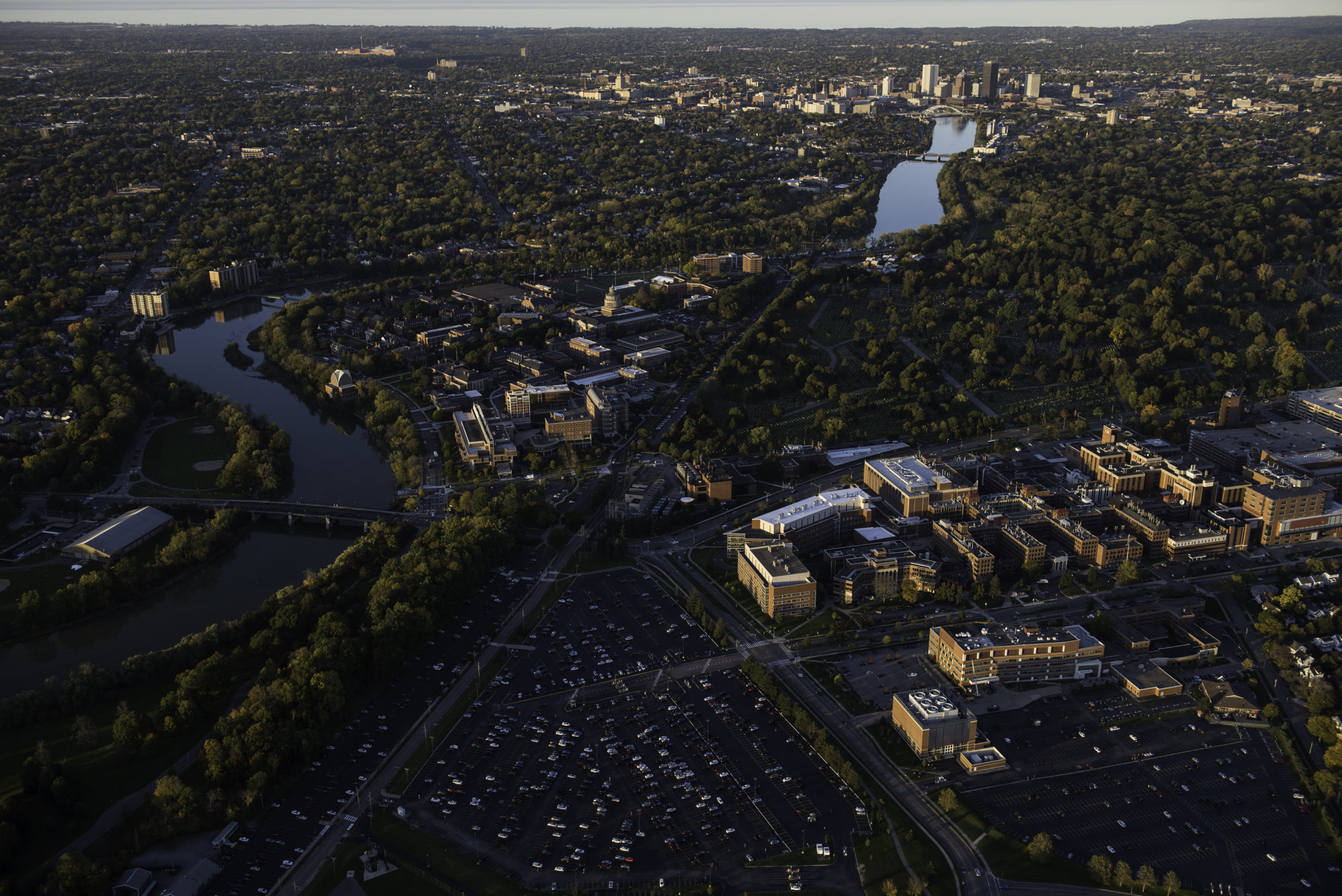 Aerial photo of University of Rochester's River Campus, Medical Center and downtown Rochester, NY alongside the Genesee River in evening