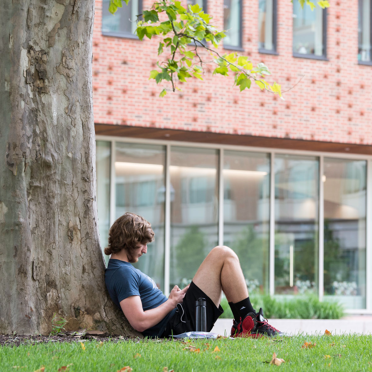 A University of Rochester student sitting on the grass, enjoying a moment of relaxation outdoors.