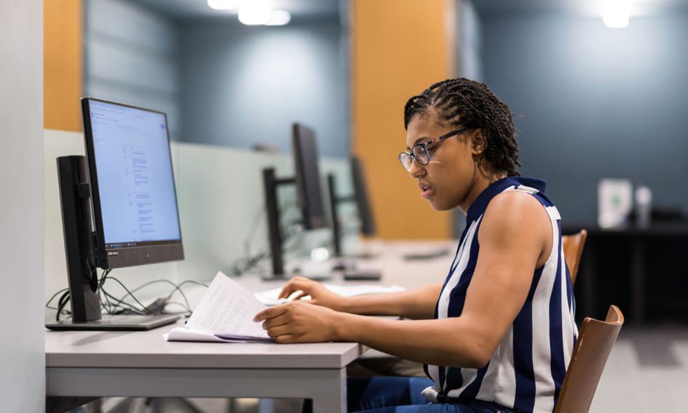 A woman at a desk with a laptop, focused on her work, representing academic life at the University of Rochester.