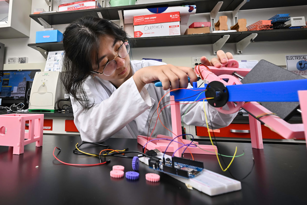 Cell and developmental biology major Jessica Wang ’28 removes plastic scraps from a 3D-printed gear on a device the team engineered called a clinostat.