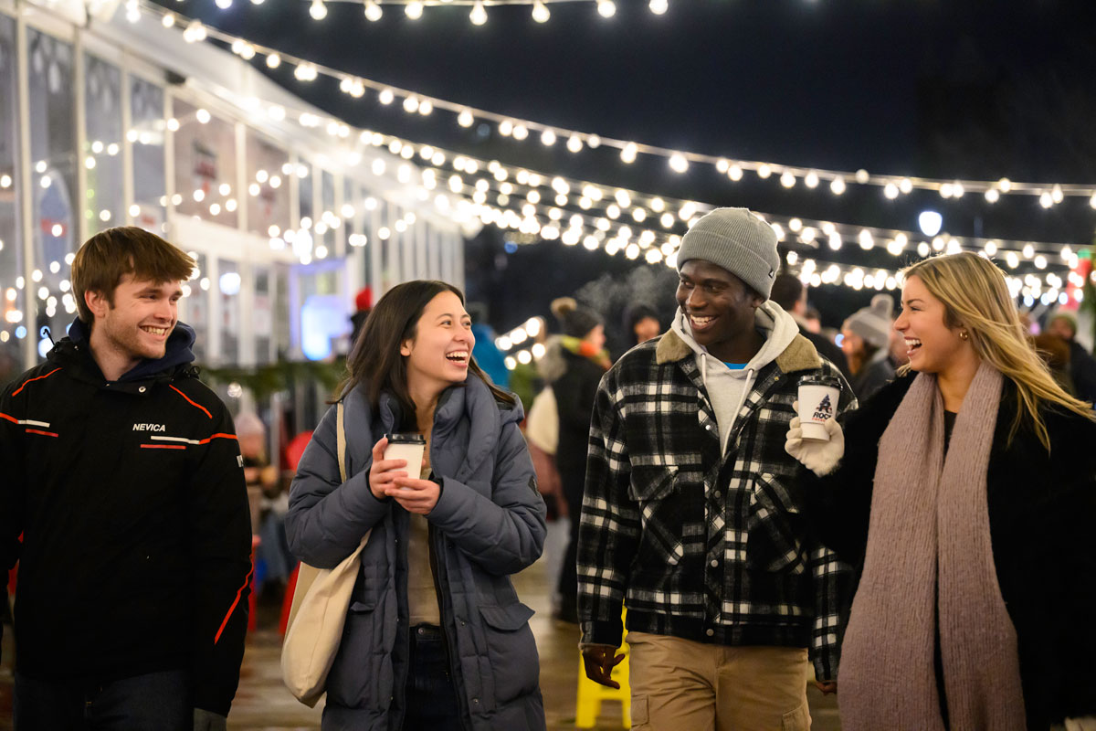 Three URochester students walking down a sidewalk at night, exploring downtown Rochester, New York.