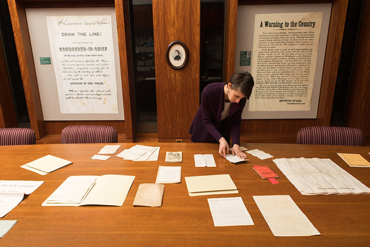 A woman is focused on a document while working in the University of Rochester library lab.