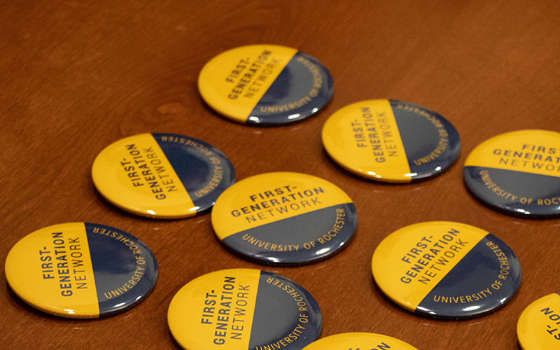 Buttons that read First-Generation Network are lined up on a wooden table.