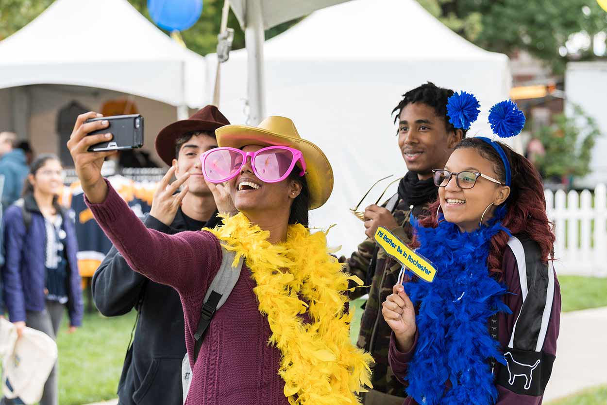 Students wearing costume props taking a selfie at University of Rochester Meliora Weekend.