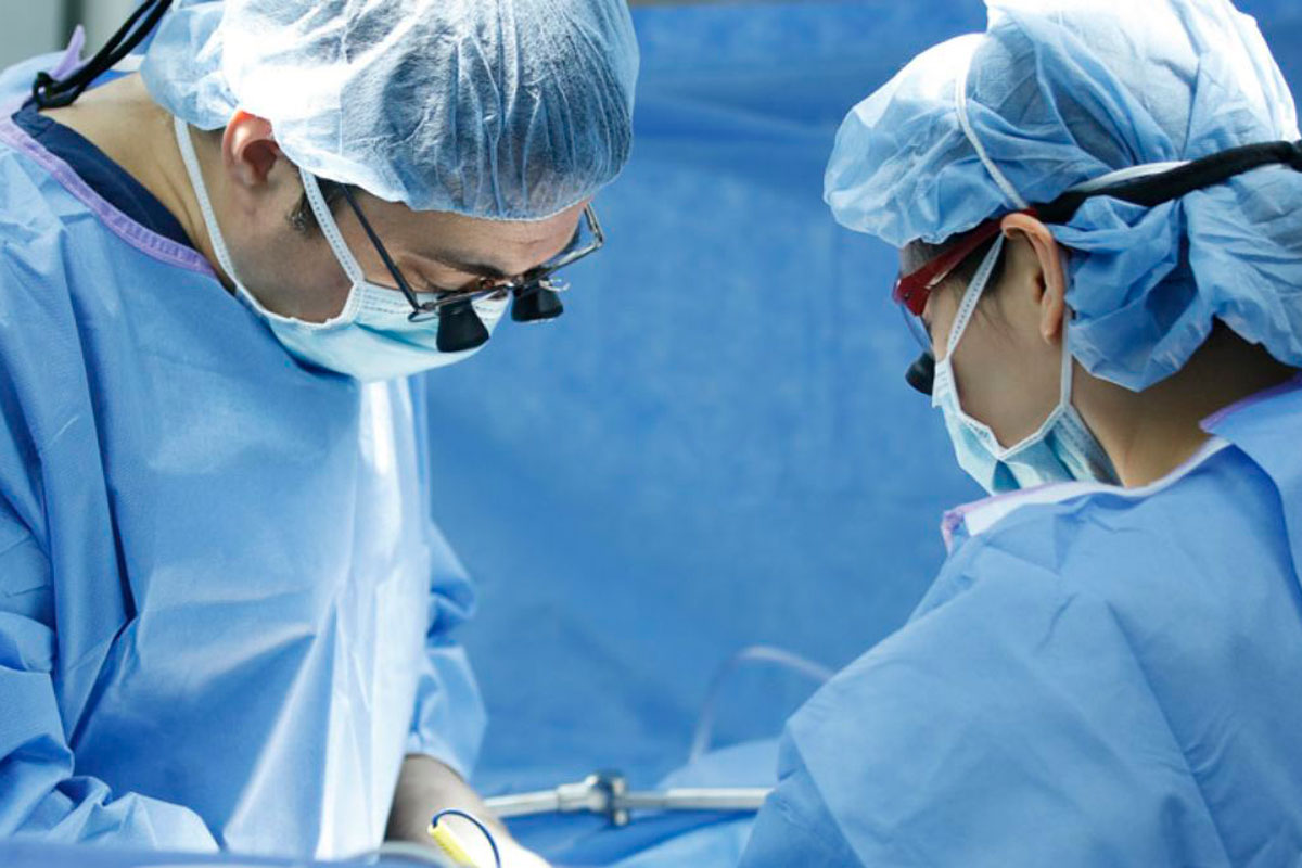 Two surgeons in blue scrubs focused on performing a surgical procedure in an operating room.
