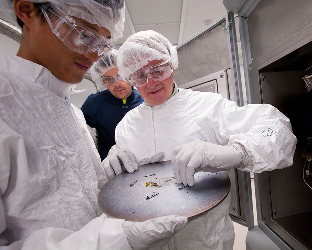Three researchers in clean suits