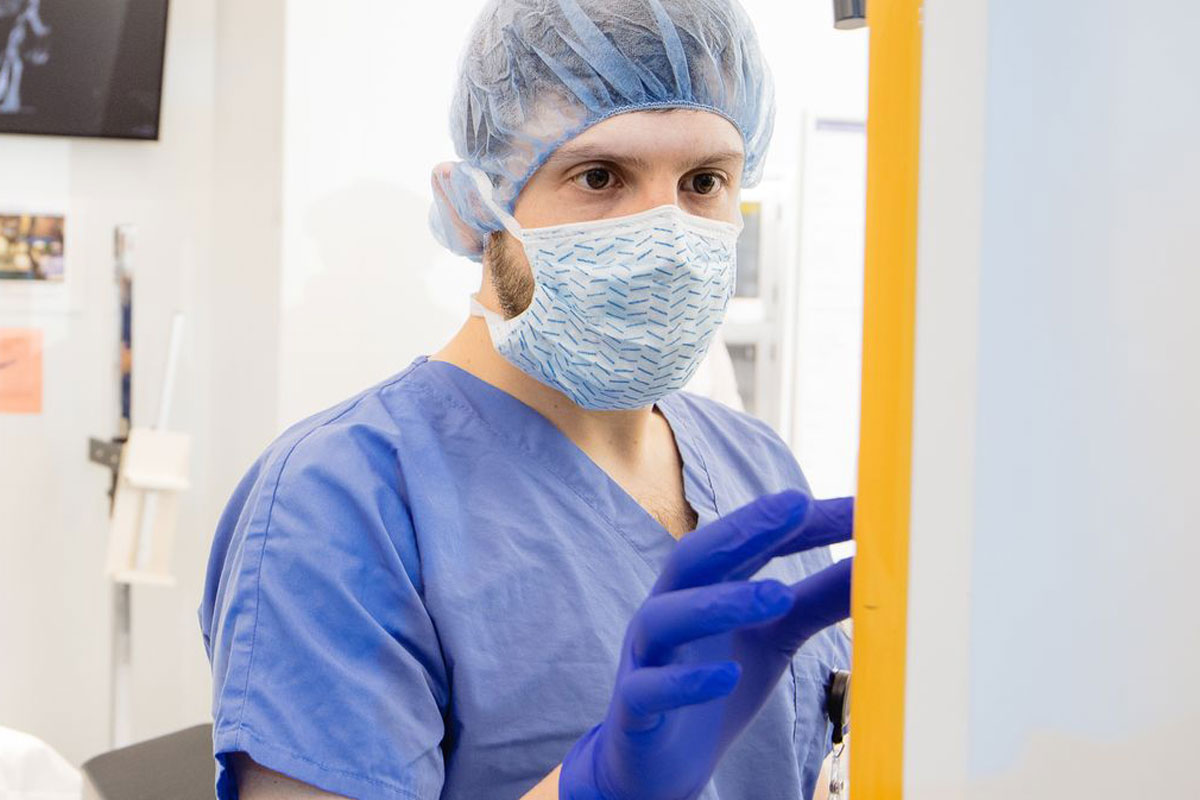A man wearing a surgical suit and blue gloves, prepared for a medical procedure.