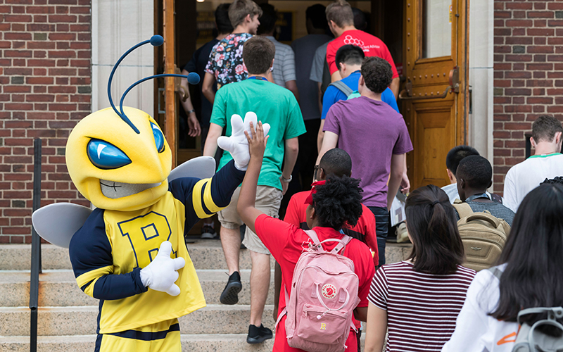 Rocky high-fives a student as they head into the Palestra with other students.