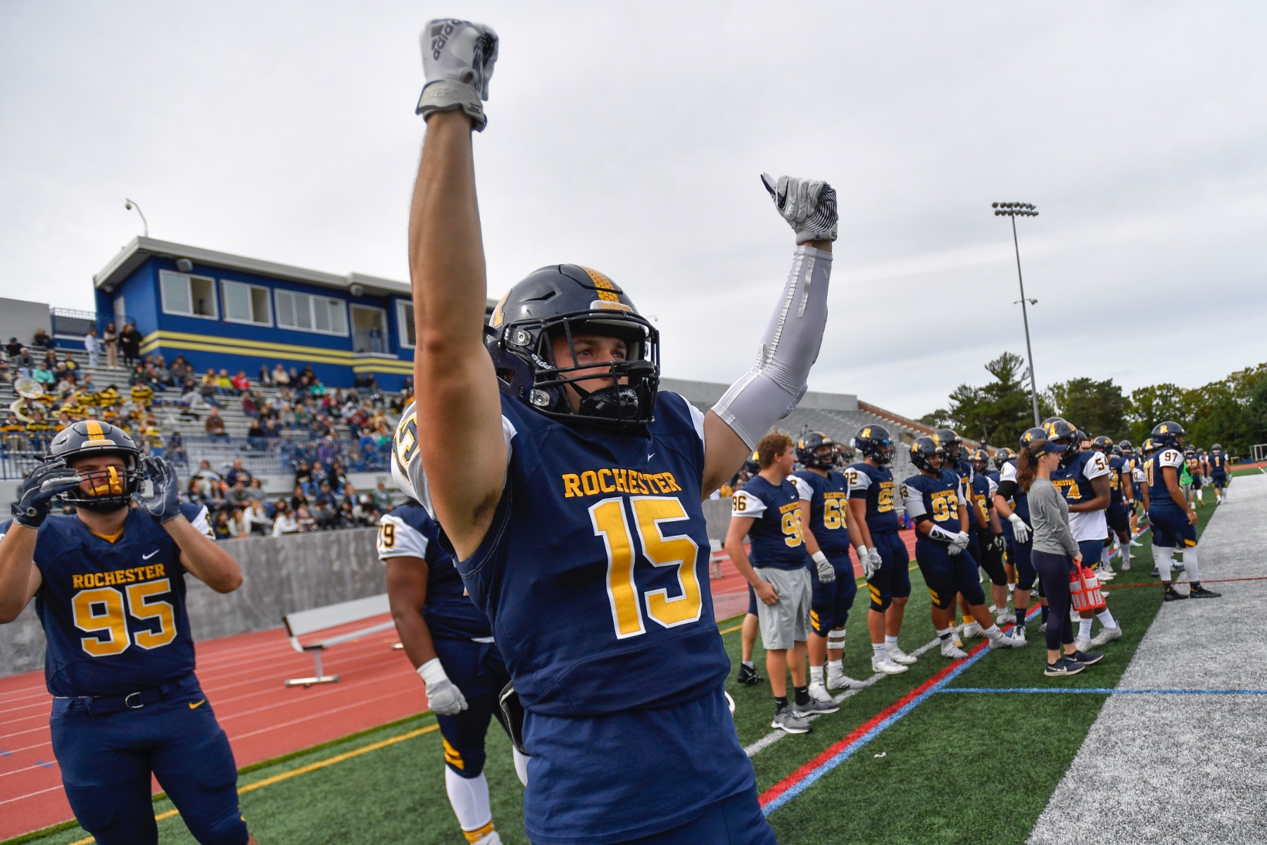A University of Rochester football athlete raises his arms in victory