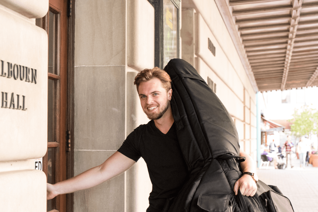 Music student with instrument entering Eastman School of Music.